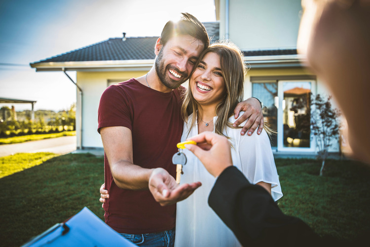 new home buyers couple receiving keys from realtor after buying new construction home