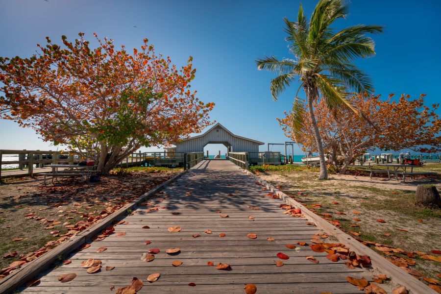 Wooden walk leading to an ocean pier in Florida on a sunny day.