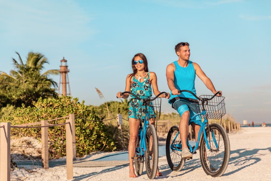 couple having fun doing biking on Florida beach with bikes